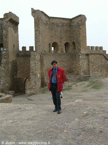 Man in red jacket walking in front of medieval castle walls