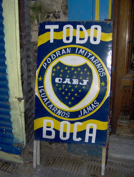 Hand-painted Boca Juniors sign leaning on a sidewalk in La Boca