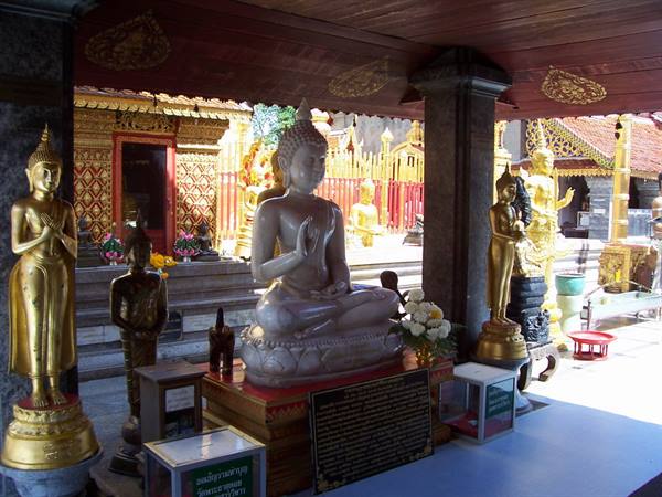 Marble Buddha statue under a pavilion surrounded by golden Buddhas and offerings