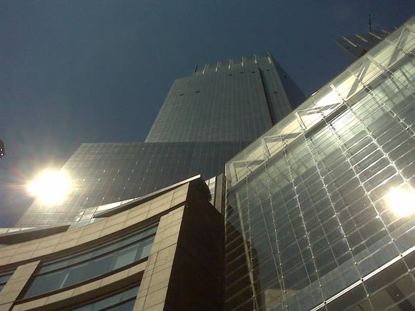 Glass and steel skyscrapers seen from below, sun reflecting on the facades