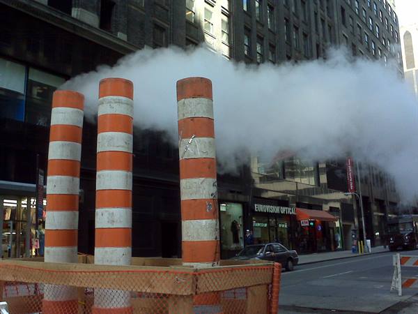 Orange and white striped stacks venting steam on a city street