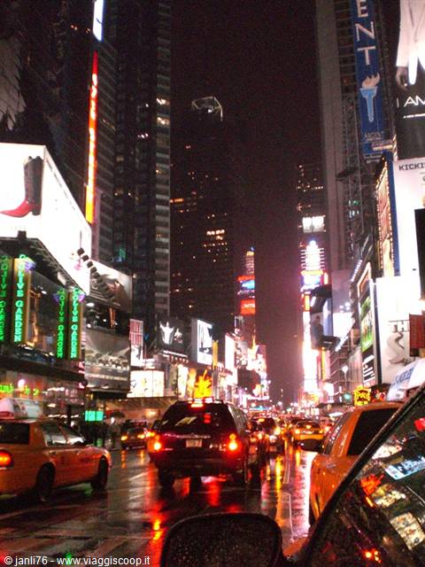 Times Square at night, yellow taxis in traffic under glowing billboards