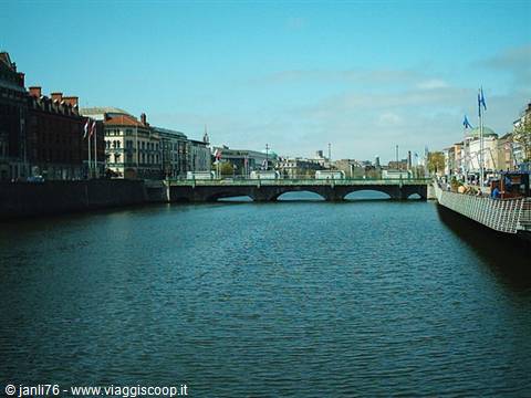The River Liffey in Dublin with a stone bridge and Georgian buildings under blue sky