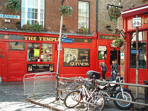 Red facade of Temple Bar in Dublin, Guinness sign, parked bicycles and motorbike