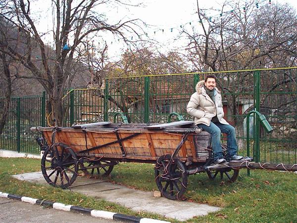 Man sitting on an old wooden cart with iron wheels