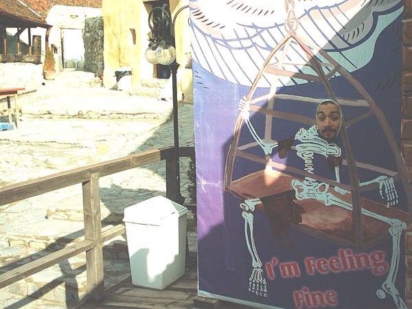 Man with face in a skeleton cutout sign, stone courtyard