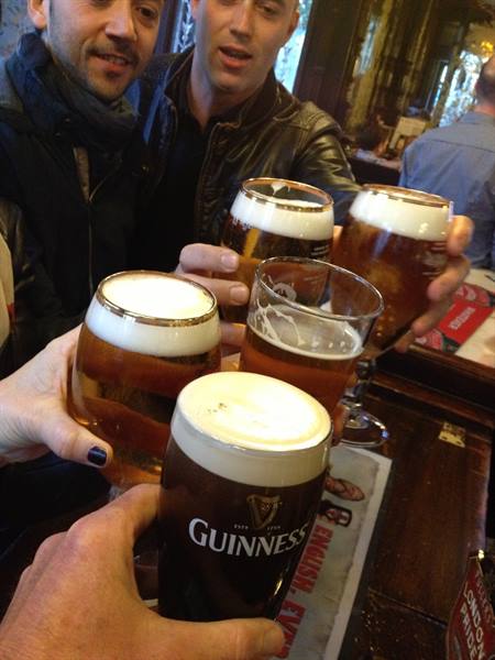 Friends toast with pints of Guinness in a wood-panelled pub