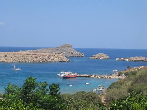 Boats anchored in a turquoise bay between arid rocks, Rhodes