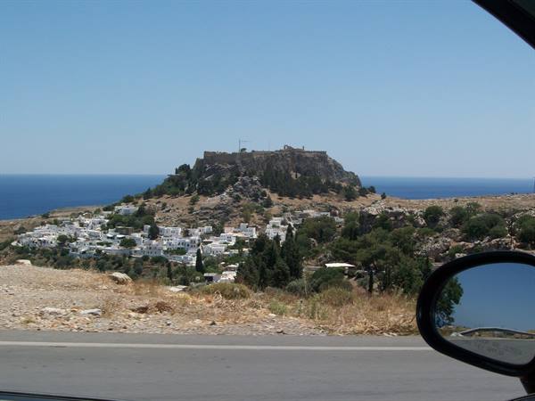 Lindos acropolis towers over whitewashed houses seen from the car