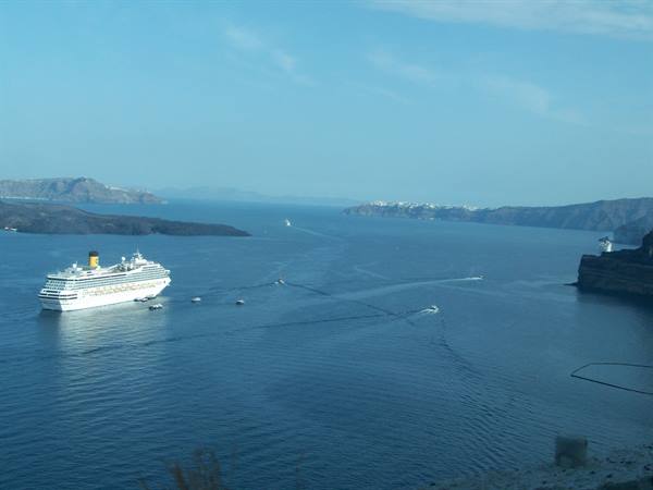 Cruise ship anchored in Santorini caldera, tenders crossing the blue water
