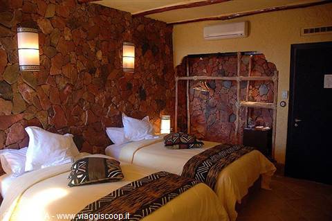 Hotel room with twin beds and reddish volcanic stone walls