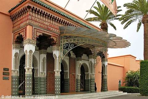 Moroccan palace entrance with carved arches, green zellige tiles and palm trees