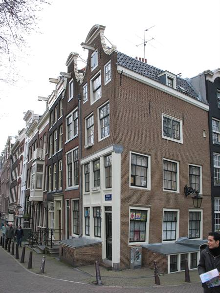 Brick canal houses with stepped gables in Amsterdam, pedestrians passing by