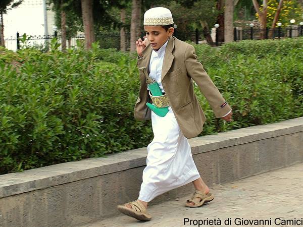 Boy in white traditional dress with jambiya dagger walking in the park