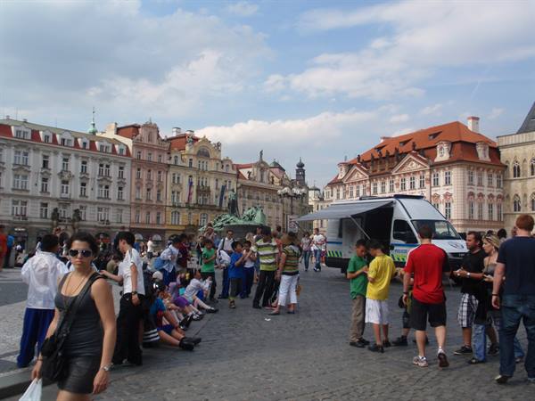 Tourists sitting around the Jan Hus monument in Prague's medieval square
