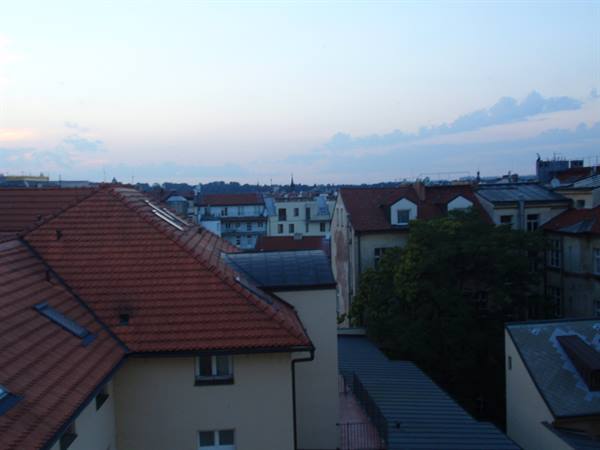 Red tiled rooftops over pale buildings under a cloudy dusk sky