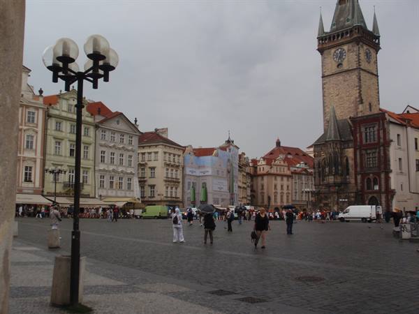 Old Town Square in Prague, tourists walking in rain past historic buildings