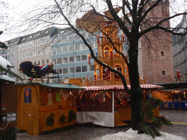 Christmas market with illuminated wooden pyramid and sleigh atop wooden stalls