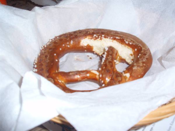A large salted pretzel sitting in a basket lined with white paper
