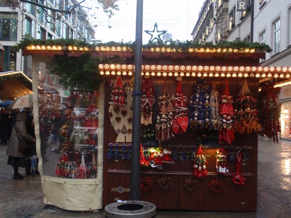 Wooden Christmas market stall with red ornaments and warm lights on a street