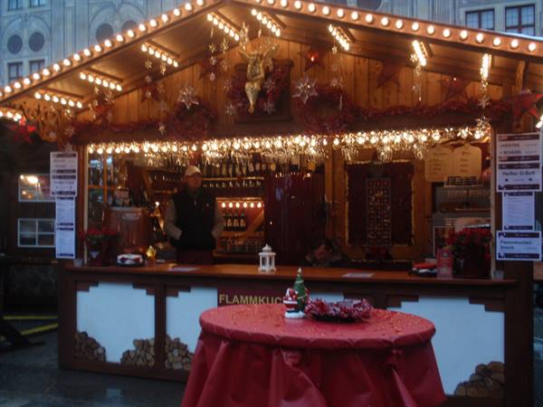 Illuminated mulled wine stall at Munich Christmas market, red round table