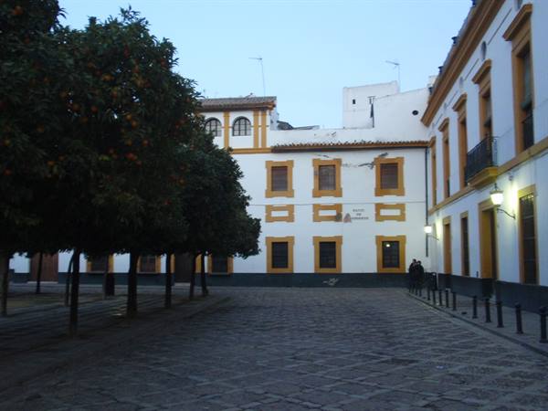 Cobblestone square with orange trees and white ochre-trimmed buildings at dusk