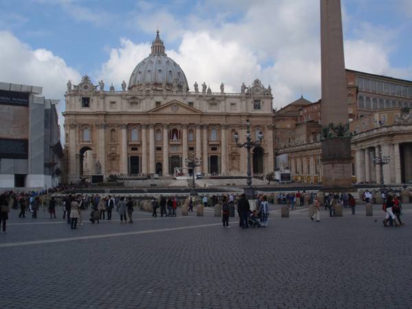 St. Peter's Square with the basilica and obelisk, tourists under a cloudy sky