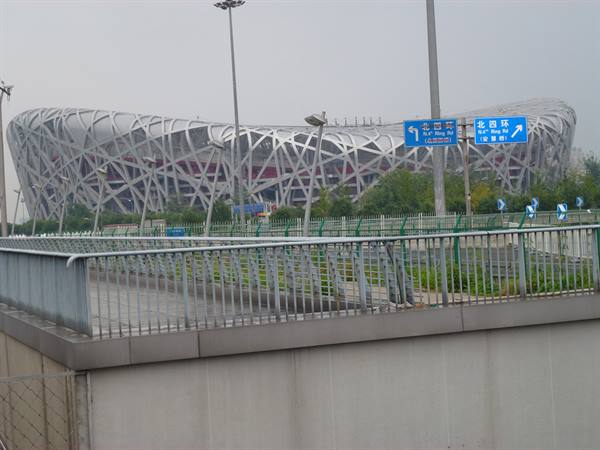 Beijing National Stadium, the Bird's Nest, seen from a concrete overpass under grey sky