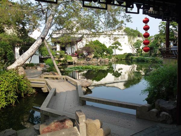 Classical Chinese garden with pond, zigzag stone bridge and red lanterns, Suzhou
