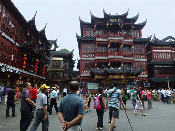 Tourists walk among traditional red wooden buildings at Yuyuan bazaar
