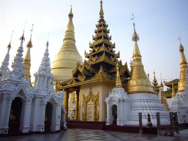 Golden stupa and white shrines under evening sky at Shwedagon