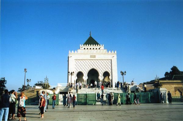 Tourists in front of the Mohammed V Mausoleum in Rabat, white marble under blue sky