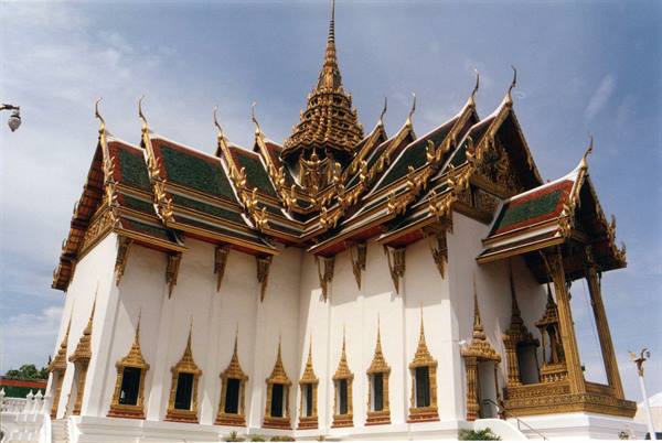 Thai temple with white walls and ornate green-gold tiered roofs, Bangkok