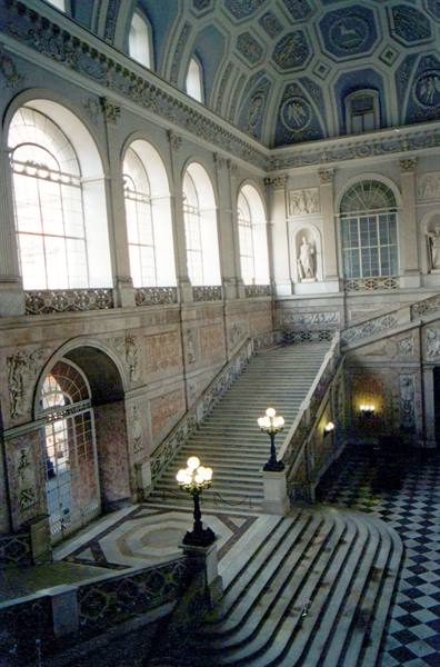 Marble grand staircase inside the Royal Palace of Naples, daylight through arched windows