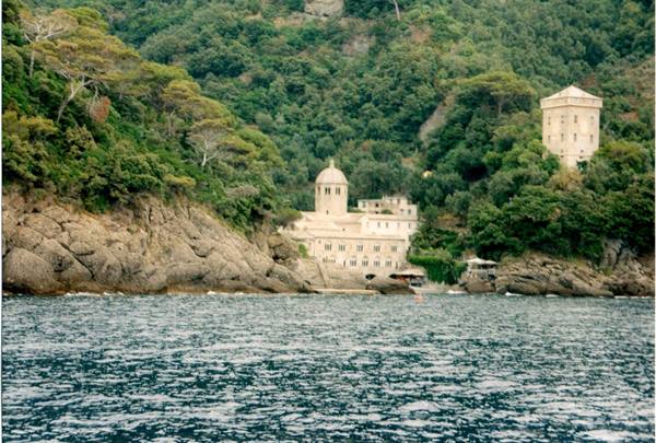San Fruttuoso abbey by the sea, rocky shore, green woods and stone tower