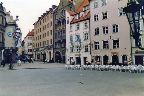Square with outdoor café tables and colorful buildings at Hofbräuhaus, Munich