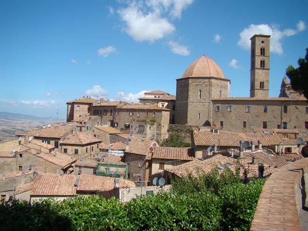 Volterra: stone baptistery with dome, bell tower and brick rooftops