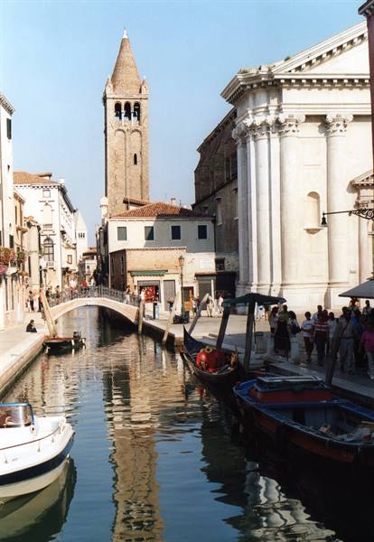 Venice canal with gondolas, bridge and bell tower, tourists along the embankment
