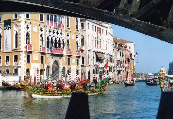 Grand Canal in Venice, gilded rowing boat with costumed rowers passing under bridge