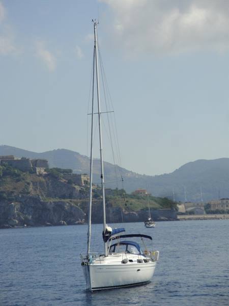 White sailboat anchored off the hilly coast of Portoferraio