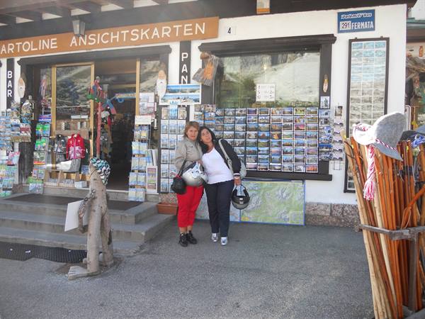 Two helmeted tourists posing outside a postcard and souvenir shop