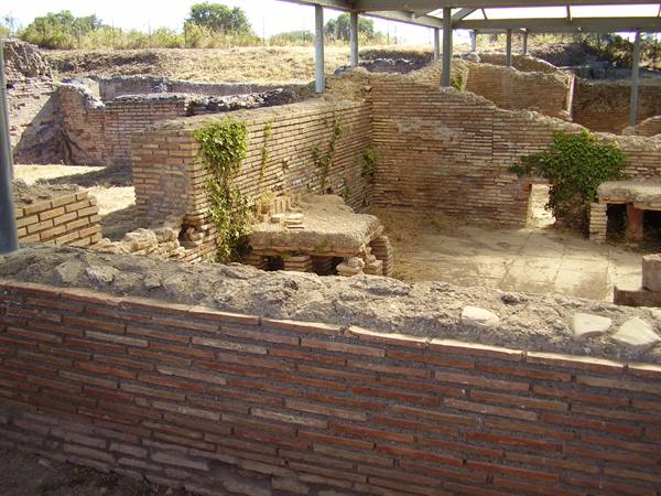 Brick walls of an ancient archaeological excavation with ivy and metal canopy