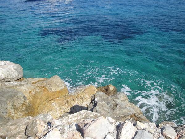 Turquoise clear water with waves breaking on white rocks
