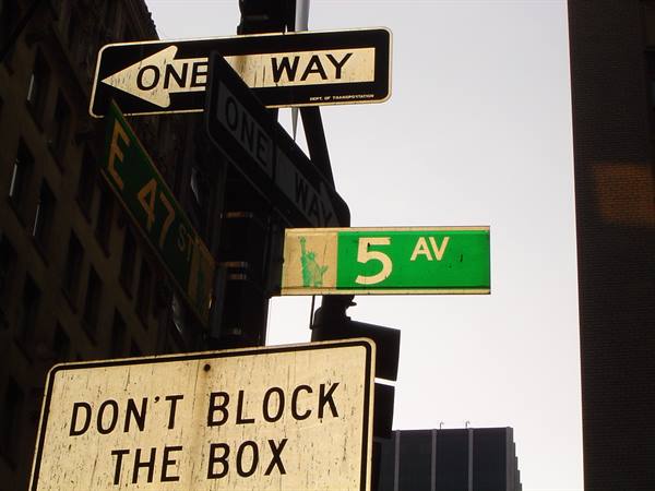 5 Av and E 47 St street signs on metal pole between skyscrapers