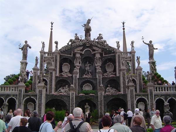 Baroque statue theater on Isola Bella, visitors admiring under cloudy sky