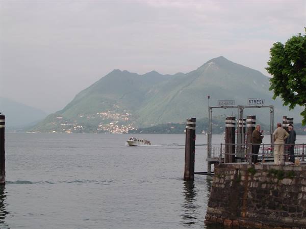 Stresa ferry pier, boat approaching the lake with mountains behind