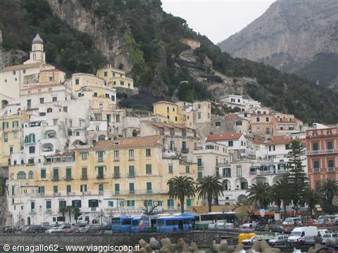 Amalfi colored houses beneath mountains, buses and cars along the seafront