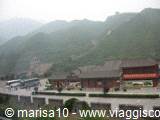 Traditional pavilions with curved roofs below green misty mountains
