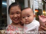 Smiling girl holding a baby wearing a white cap