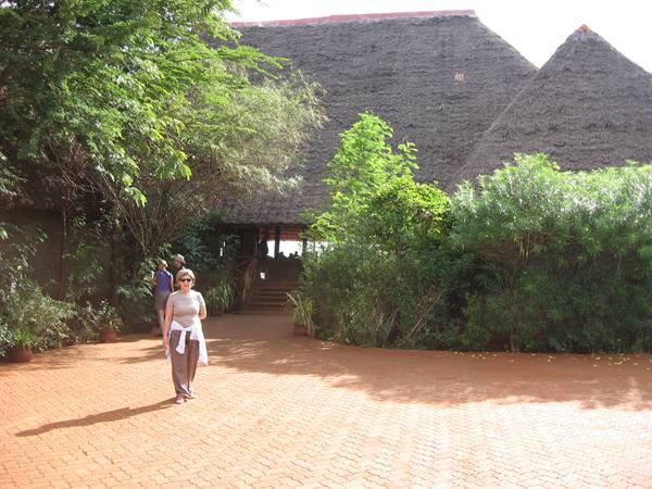 Tourist walking on brick pavement in front of thatched-roof lodge